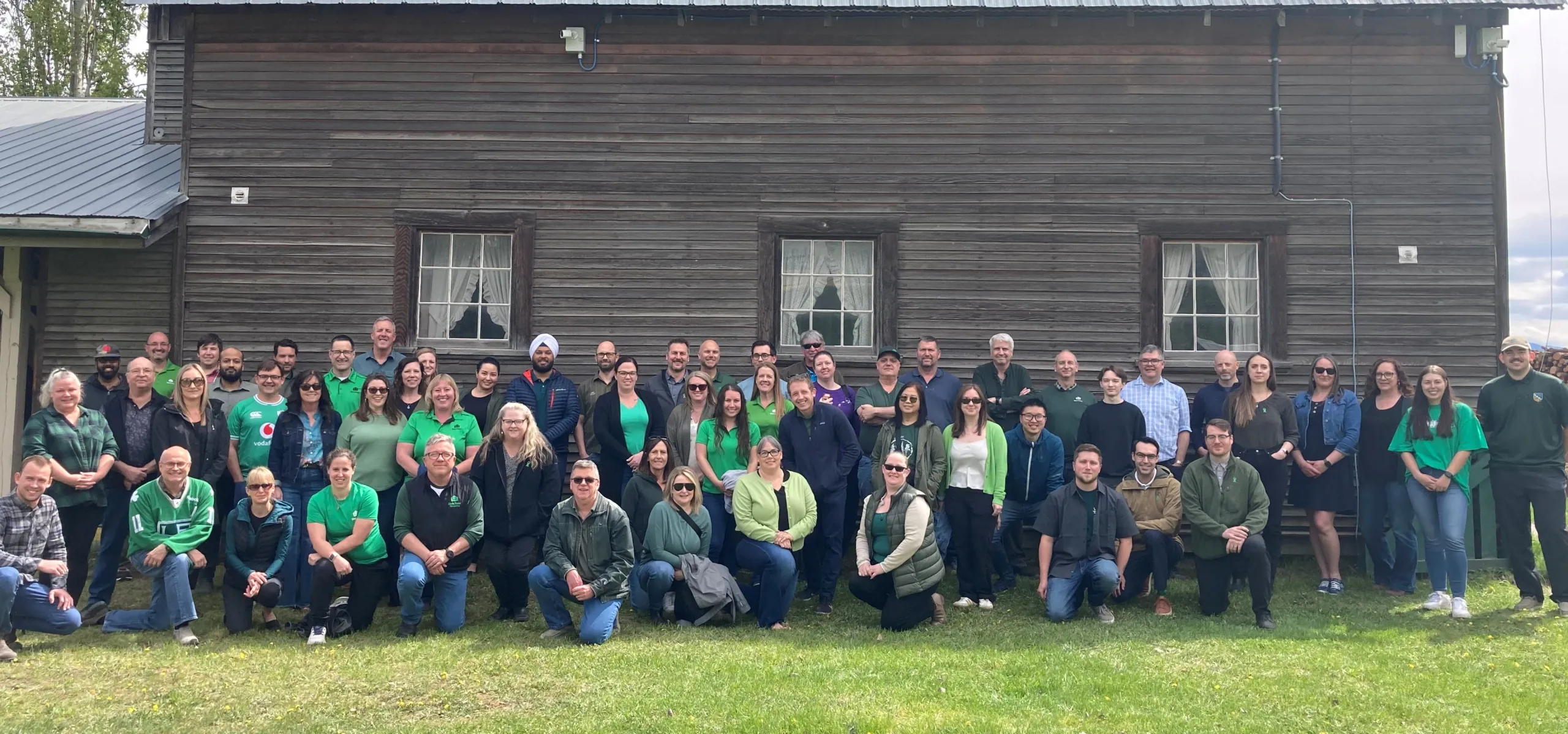 West Fraser team members pose in front of a wooden barn structure, on the site of the company's Quesnel location.