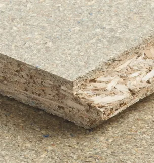 Close-up of a textured particle board showing layers of compressed wood chips and fibers on a flat surface.